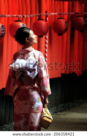 A woman dressed in traditional Japanese costume poses under Tori gates at the Fushimi-Inari shrine in Kyoto during the time of Gion Matsuri and before the Yoi-Miya and Motomiya festivals in July 2014