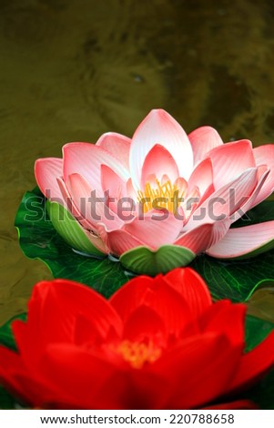Pink and red decorative plastic flowers in a pond