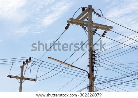 Cables hung on concrete poles against blue sky in bright sunlight