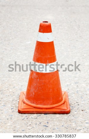 A single plastic traffic cone on the middle of a tarmac road