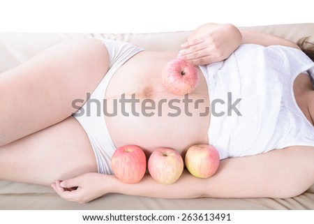 Pregnant belly woman with apples around and hold an apple.