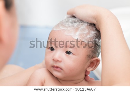 Mother give a bath her newborn baby in bathroom focus at the eye Mother give a bath her newborn baby in bathroom focus at the eye