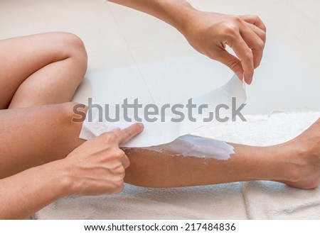Women are pasting fabric for waxing legs by herself.
