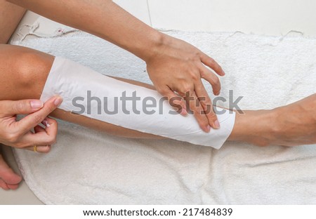 Women are paste fabric for waxing legs by herself.