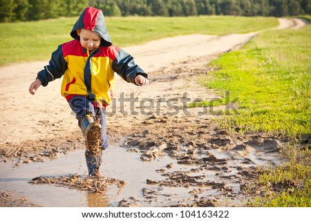 Boy splashing in puddle, having fun