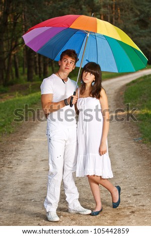Couple in the summer rain with a rainbow umbrella