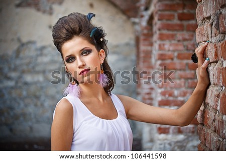 Fashion portrait of a cute brunette near a brick wall