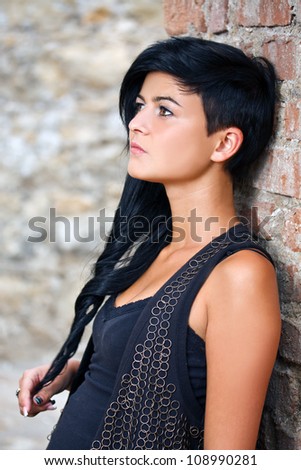 Beautiful young woman near brick wall