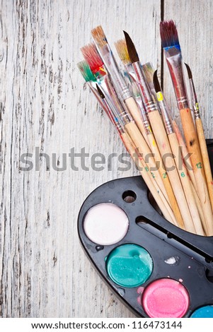Watercolor paints set with brushes on wooden background
