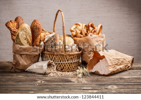 Composition with bread and rolls in wicker basket and paper bag