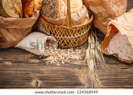 Composition with bread and rolls in wicker basket and paper bag