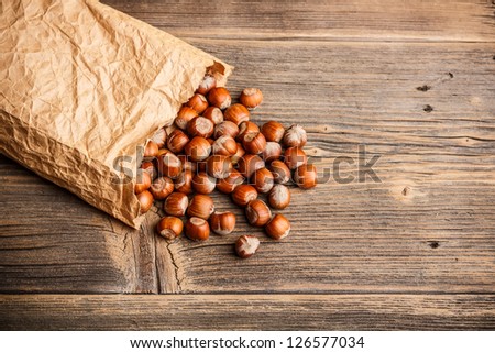 Paper bag with hazelnuts on wooden background