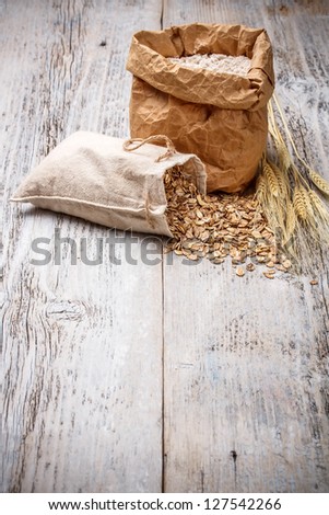 Oat flakes spilling from the burlap bag on old wooden table