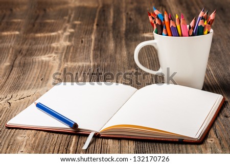 White cup with colorful pencils and notebook