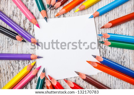 Multicolored pencils and paper on rustic wooden table