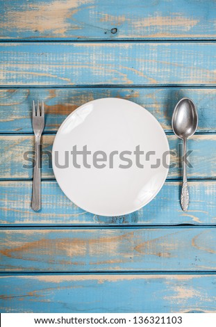 Empty white plate on weathered blue wooden table