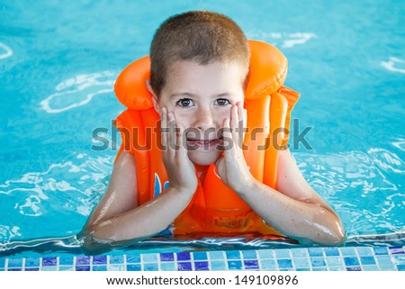 Child in life jacket posing in swimming pool