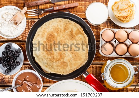 Frying pan with pancake and pancake ingredients