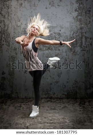 Young beautiful dancer posing on a grunge concrete wall background