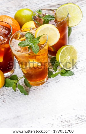 Glasses of ice tea with ice-cubes on wooden table