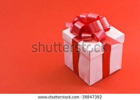 A white box tied with a red satin ribbon bow. A gift for Christmas, Birthday, Wedding, or Valentine's day