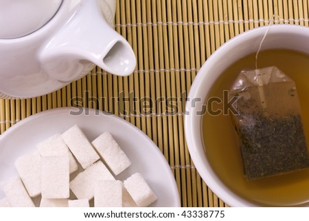 white tea pot with cup and sugar in bamboo background