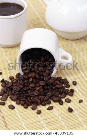 coffee cup and spilled coffee beans, in bamboo background