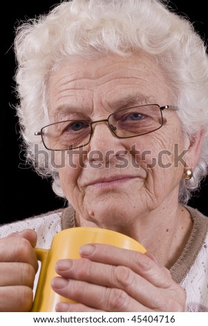 elderly woman holding coffee or tea cup over black background