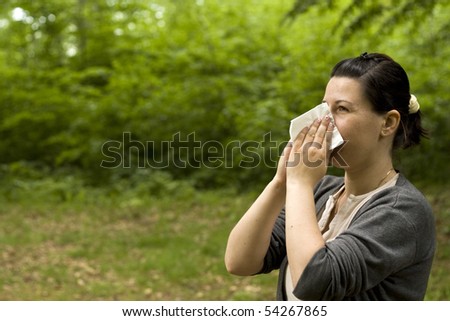 brunette woman having a pollen allergy in the forest