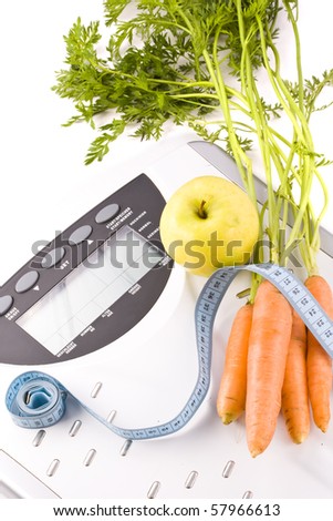 Carrots and apple surrounded by a measuring tape on a white bathroom scale. Blank display.