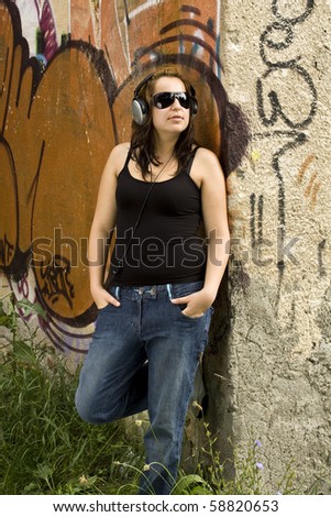 portrait of young woman with headphones at graffiti wall