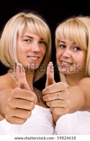 two beautiful women giving thumbs-up on a black background
