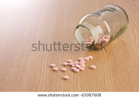 Pills spilled from a pill bottle on wooden background