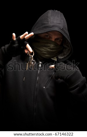 Thief with keys aiming into a camera - isolated on black background