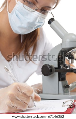Serious female scientist writing on her clipboard in front of a microscope, focus on the hand