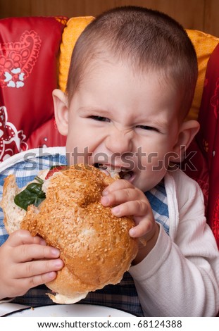 Little happy boy eating a tasty hamburger