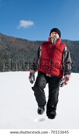 Young man walking on the snow in winter