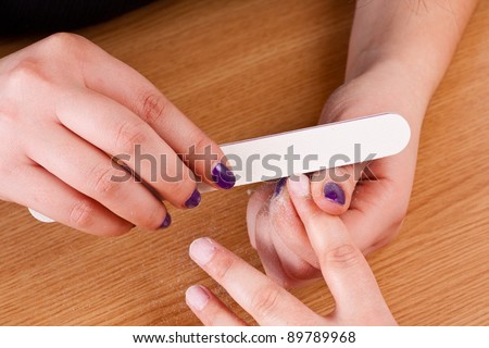 Applying manicure - processing nails with emery nail-file