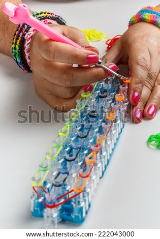 Young woman making a rubber loom bracelet with a hook