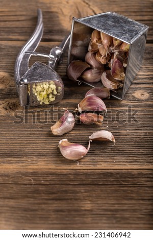 Garlic crushed and garlic press on rustic wooden board