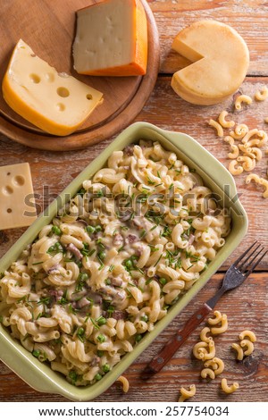 Mac and cheese. Cheesy pasta in green bowl on wood background