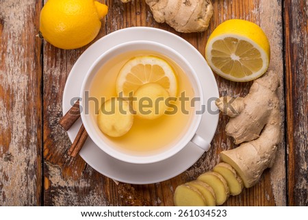 White cup with ginger tea on rustic wooden board