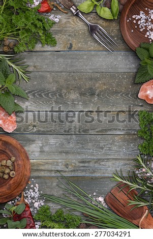 Various green herbs arranged as a frame on weathered wooden board