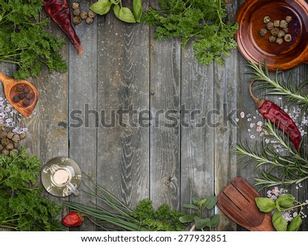 Various herbs arranged as a frame on weathered wooden background
