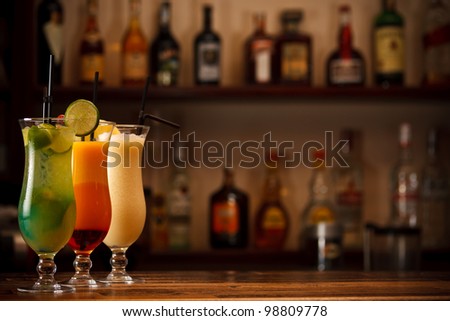 Three tropical mixed drinks, shot in bar with space for copy