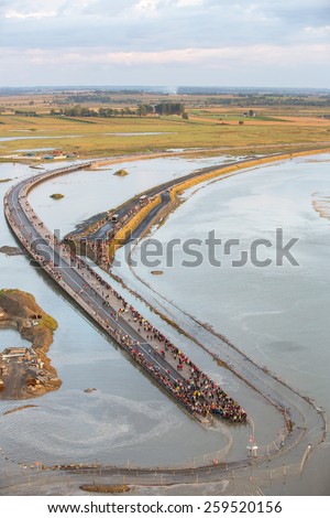 Mont Saint Michel, France - August 12: View of the road leading to Mont Saint Michel, France during a high tide at sunset on August 12, 2014.