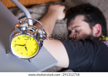 Man sleeping in bed with an alarm