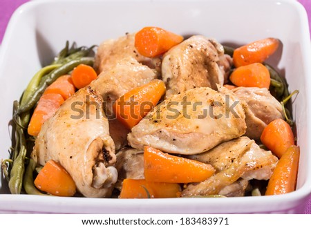 Fried chicken with baby carrots in a white bowl on a dinner table