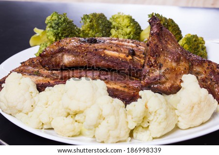 Grilled pork ribs meat with cooked cauliflower and broccoli on the withe plate