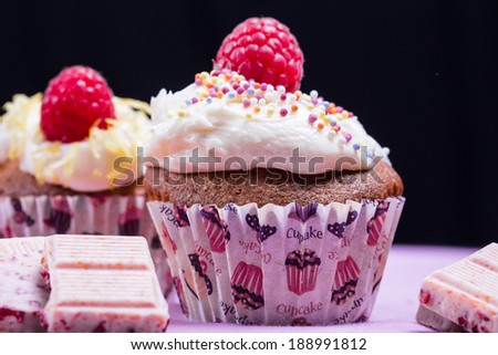 cupcakes with raspberries and fruity chocolate on pink and black background